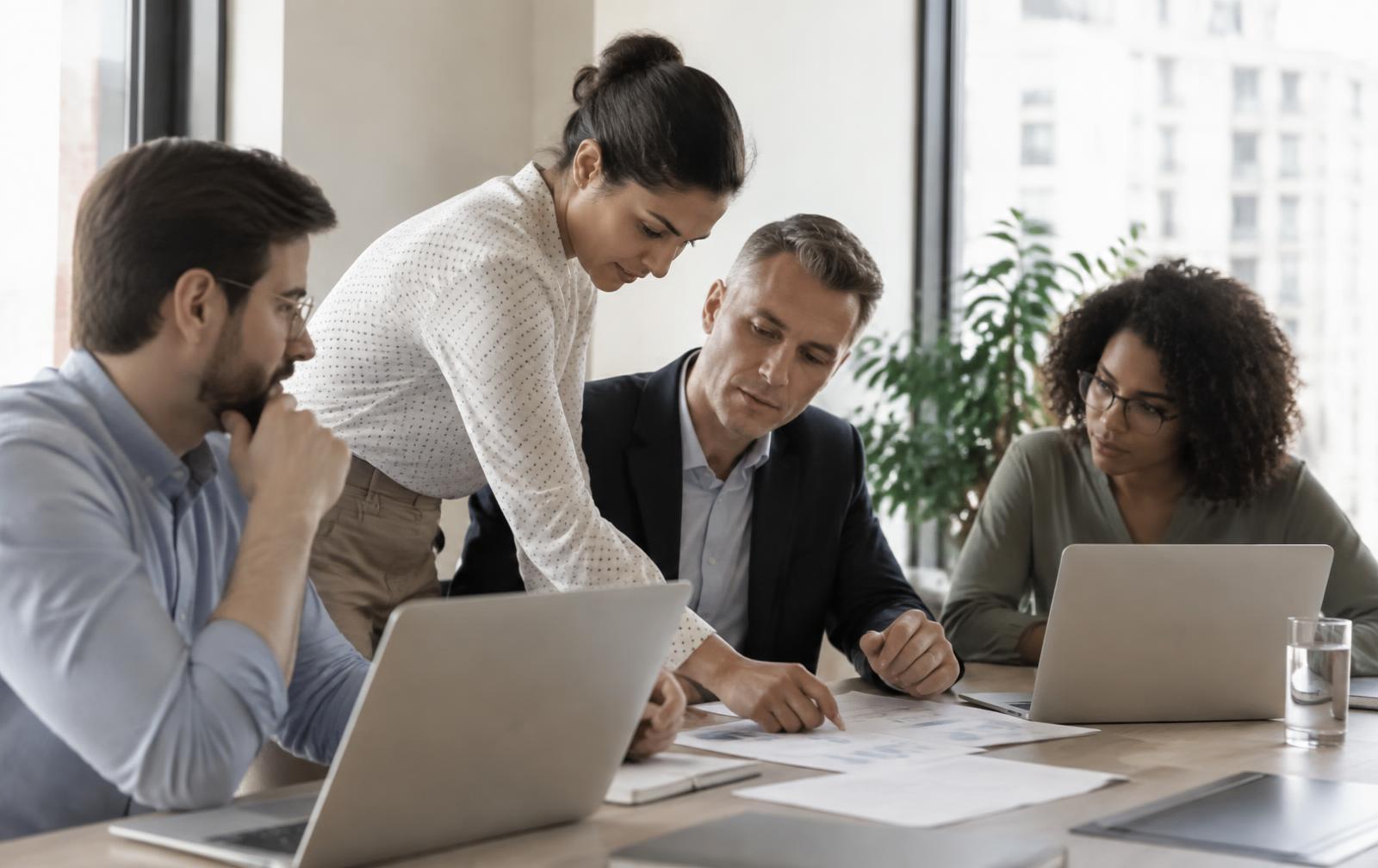 Profissionais de negócio e de tecnologia analisando informações juntos em uma mesa de trabalho